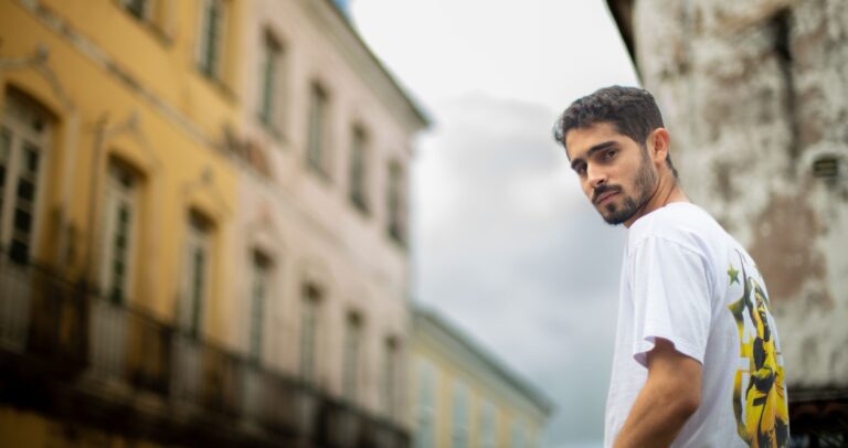 Man posing outdoors with historical Salvador buildings in the background.