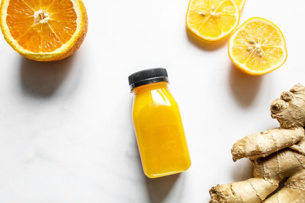 Bright and vibrant citrus juice with fresh ginger on a white background, perfect for health-focused content.