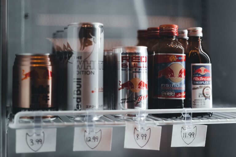 Variety of energy drinks displayed with prices on a refrigerator shelf.