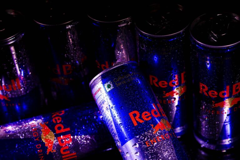 Close-up of Red Bull energy drink cans with refreshing water droplets, showcasing branding.