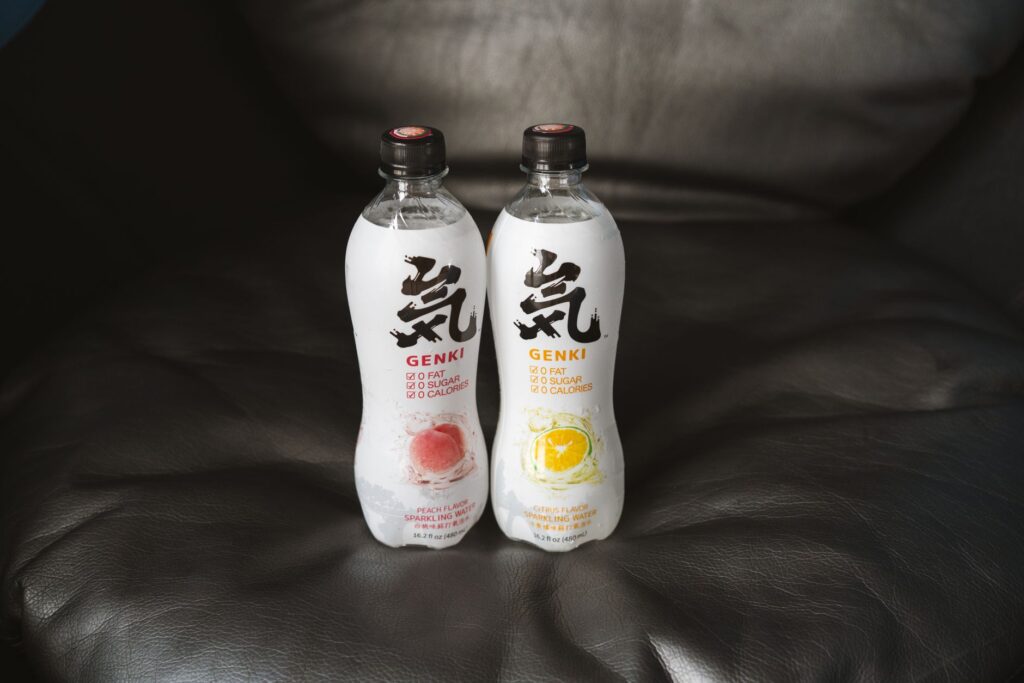 Close-up of Genki flavored sparkling water bottles placed on a leather couch, showcasing packaging and design.
