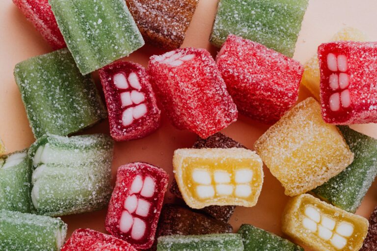 From above of multicolored gummy candies with white filling stacked together on beige tabletop in confectionery shop