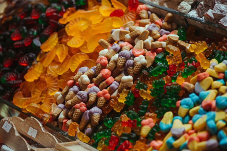 Vibrant selection of assorted gummy candies in a market stall, showcasing various shapes and colors.