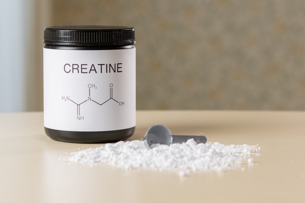 Uma Garrafa De Creatina Ao Lado De Uma Colher Em Uma Mesa E333ulMOZ_o